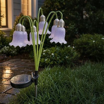 Solar flower lights glowing in dewy garden at dusk