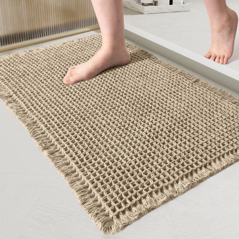 Khaki waffle-weave bath mat with fringe under bare foot