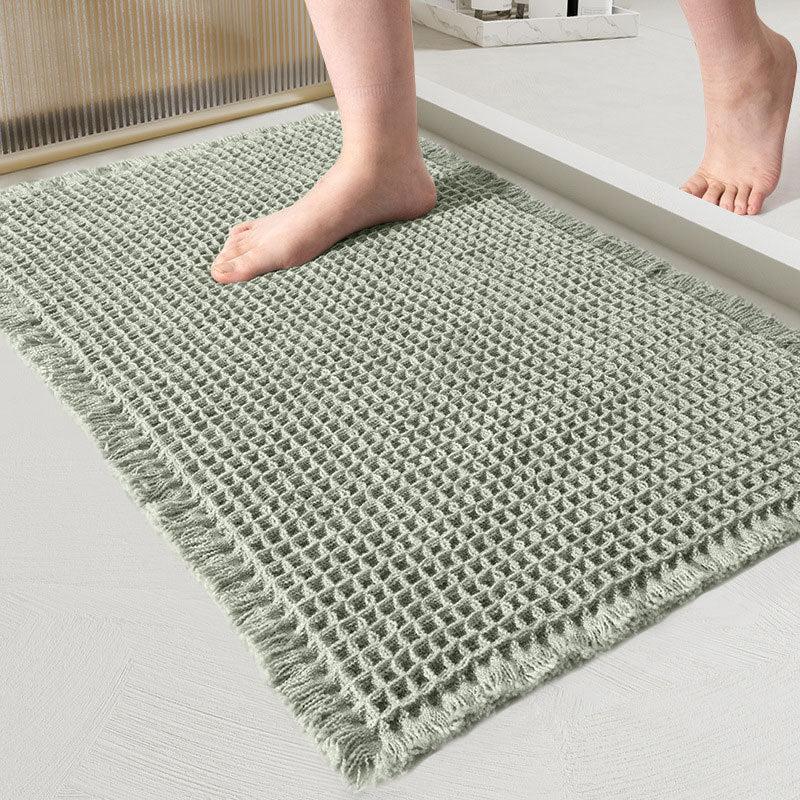Sage green waffle-weave bath mat with fringed edges