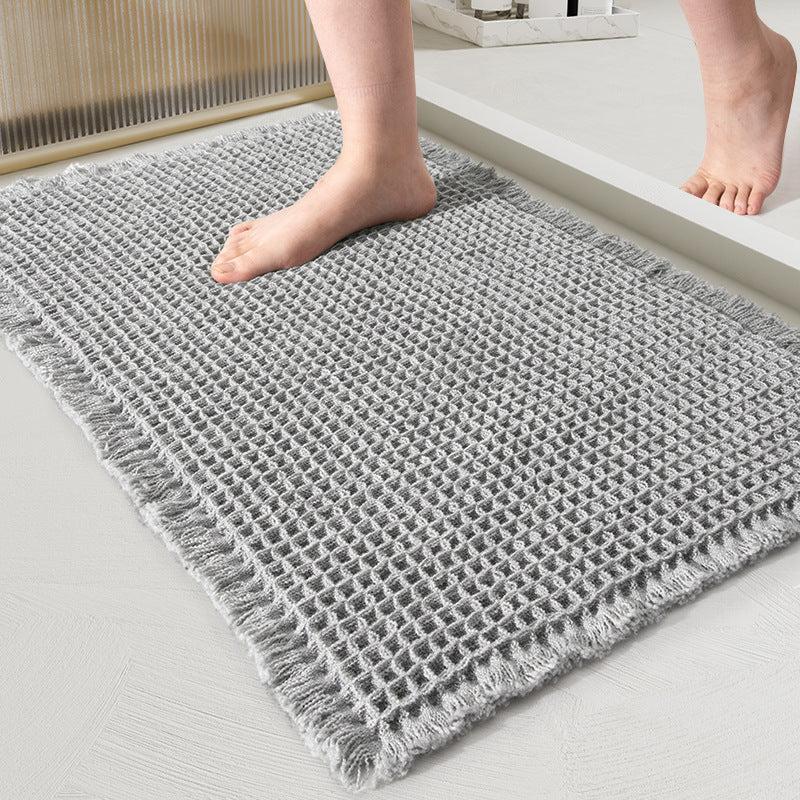 Light gray waffle-weave bath mat with fringed edges