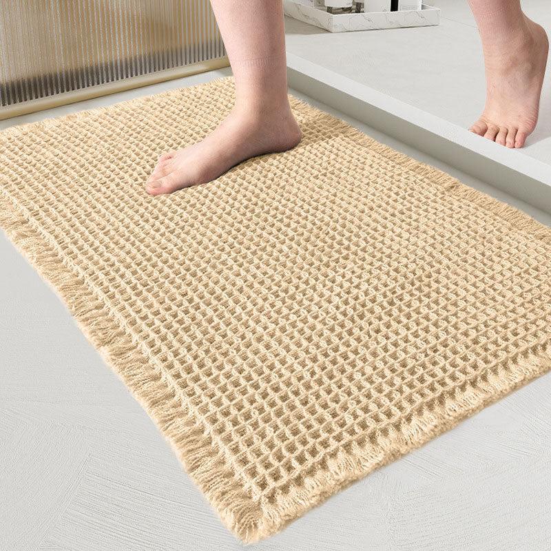 Beige waffle-weave bath mat with fringed edges